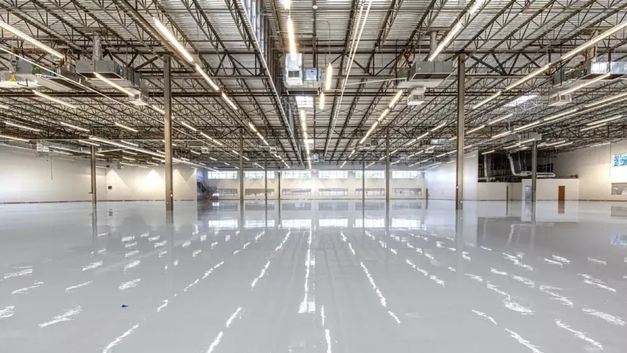Empty warehouse interior with a seamless glossy epoxy coated floor and exposed steel truss ceiling